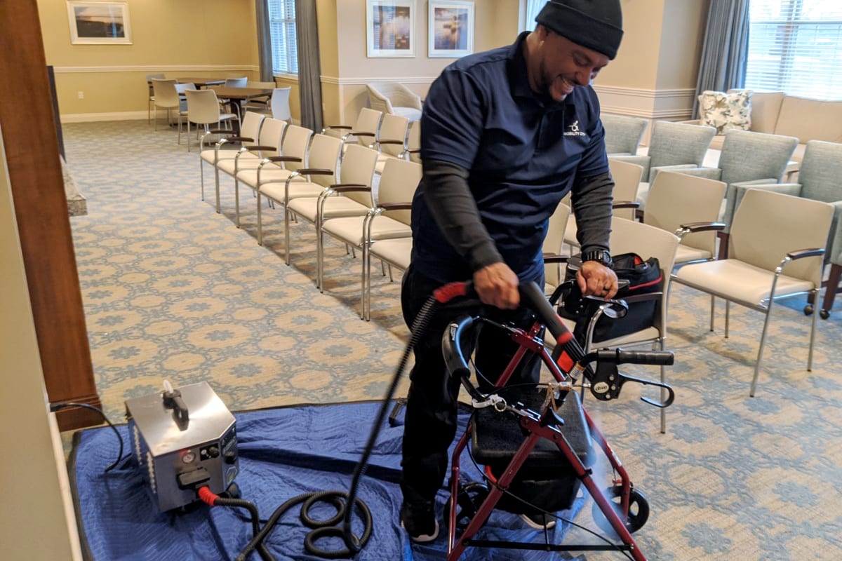 Technician Andre steam cleaning a walker in a hallway