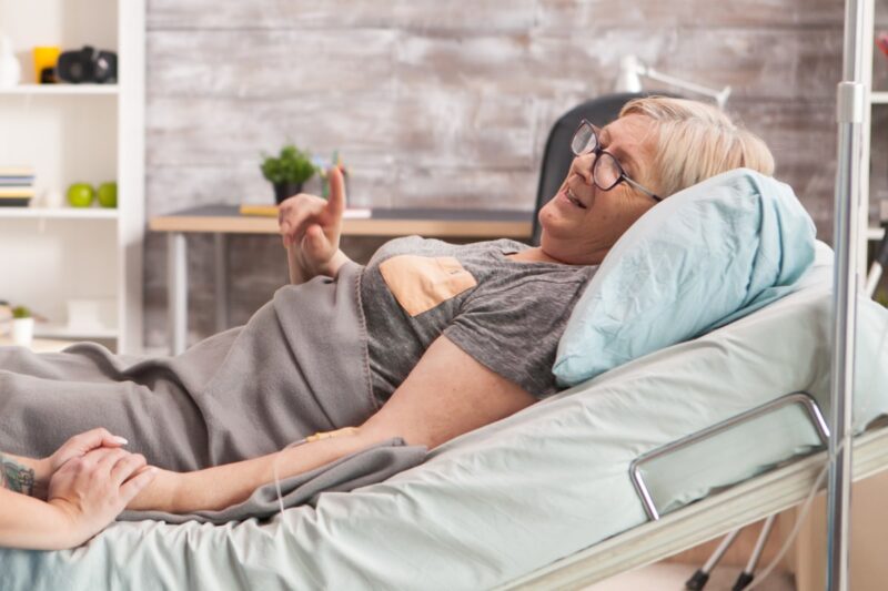 Elderly woman lying in a hospital bed in her own home