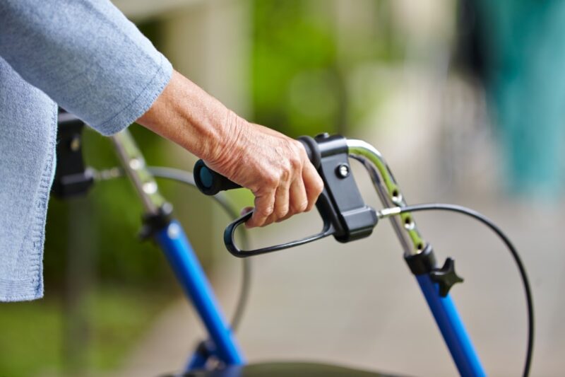 Close up of elderly woman's hands gripping handlebars of a walker