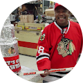 man in Chicago Blackhawks jersey smiling and holding hockey stick